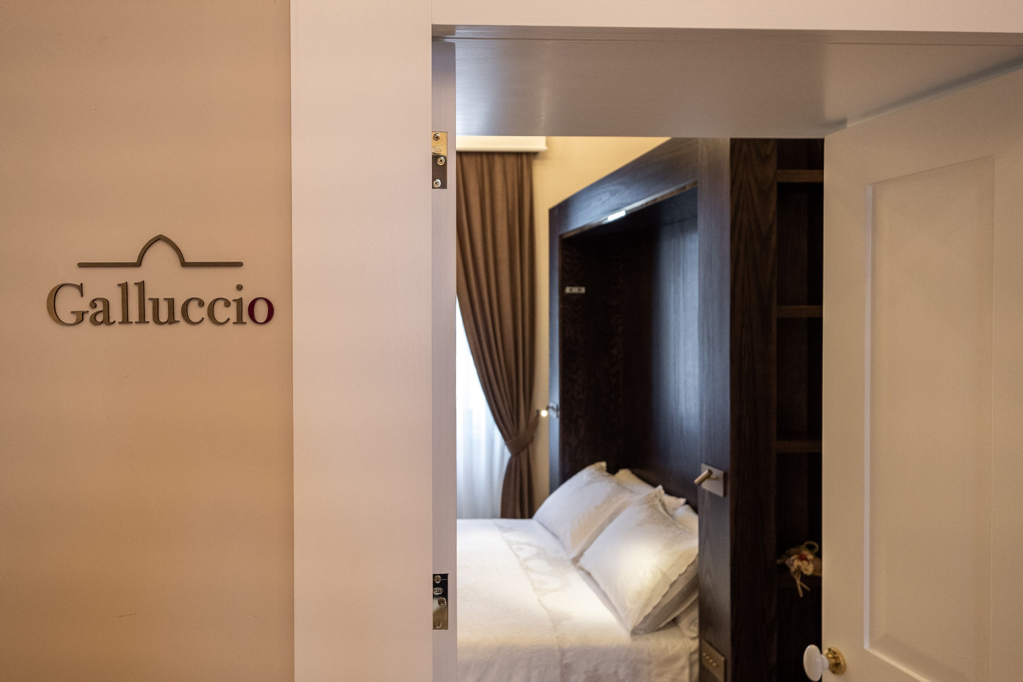 A hotel room with a bed, a wardrobe, and a door.