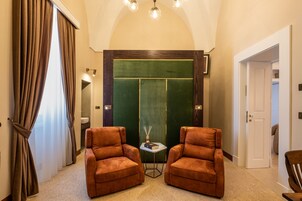 Una habitación con dos sillones de cuero marrón, una mesita con un libro y una vela, y una pared de acento verde.