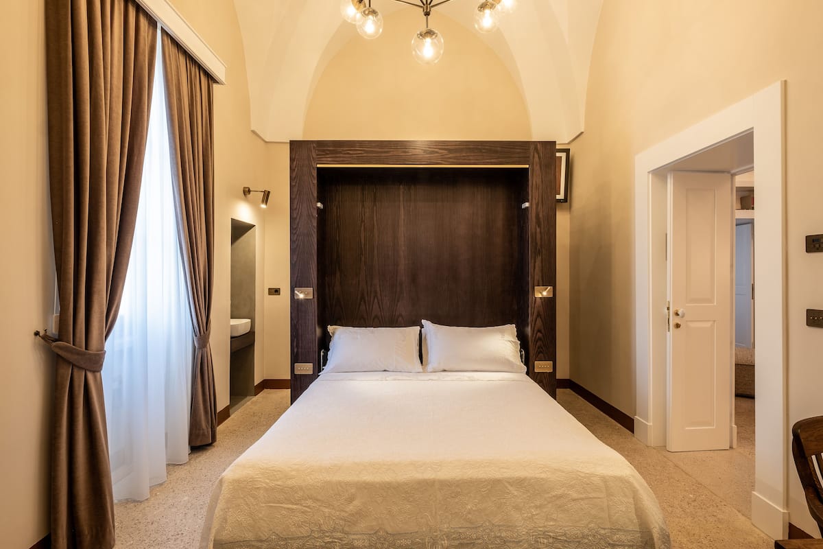 Una habitación de hotel con una cama grande, cabecera de madera y un candelabro.