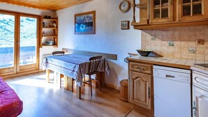 A cozy kitchen with wooden cabinets, a dining table, and a dishwasher.