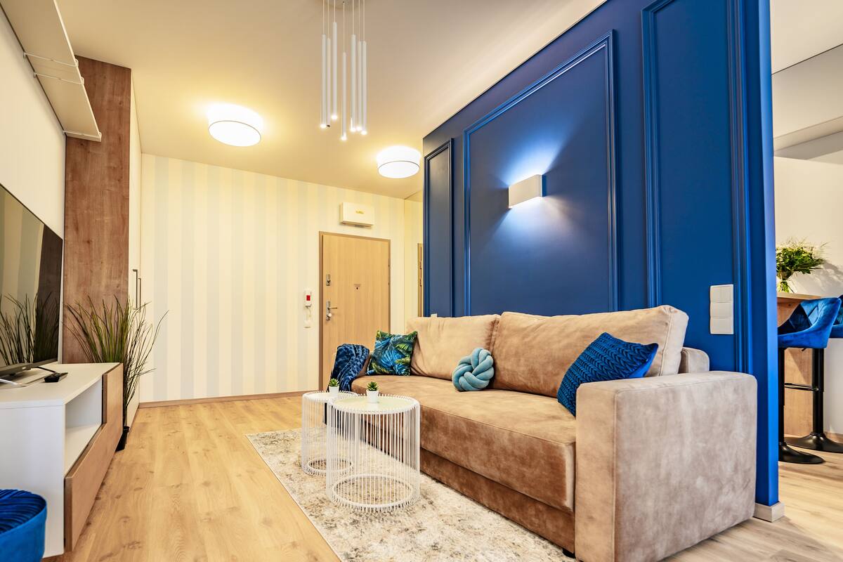 Un salón moderno con un sofá color beige, un televisor de pantalla plana y una mesa de centro blanca.