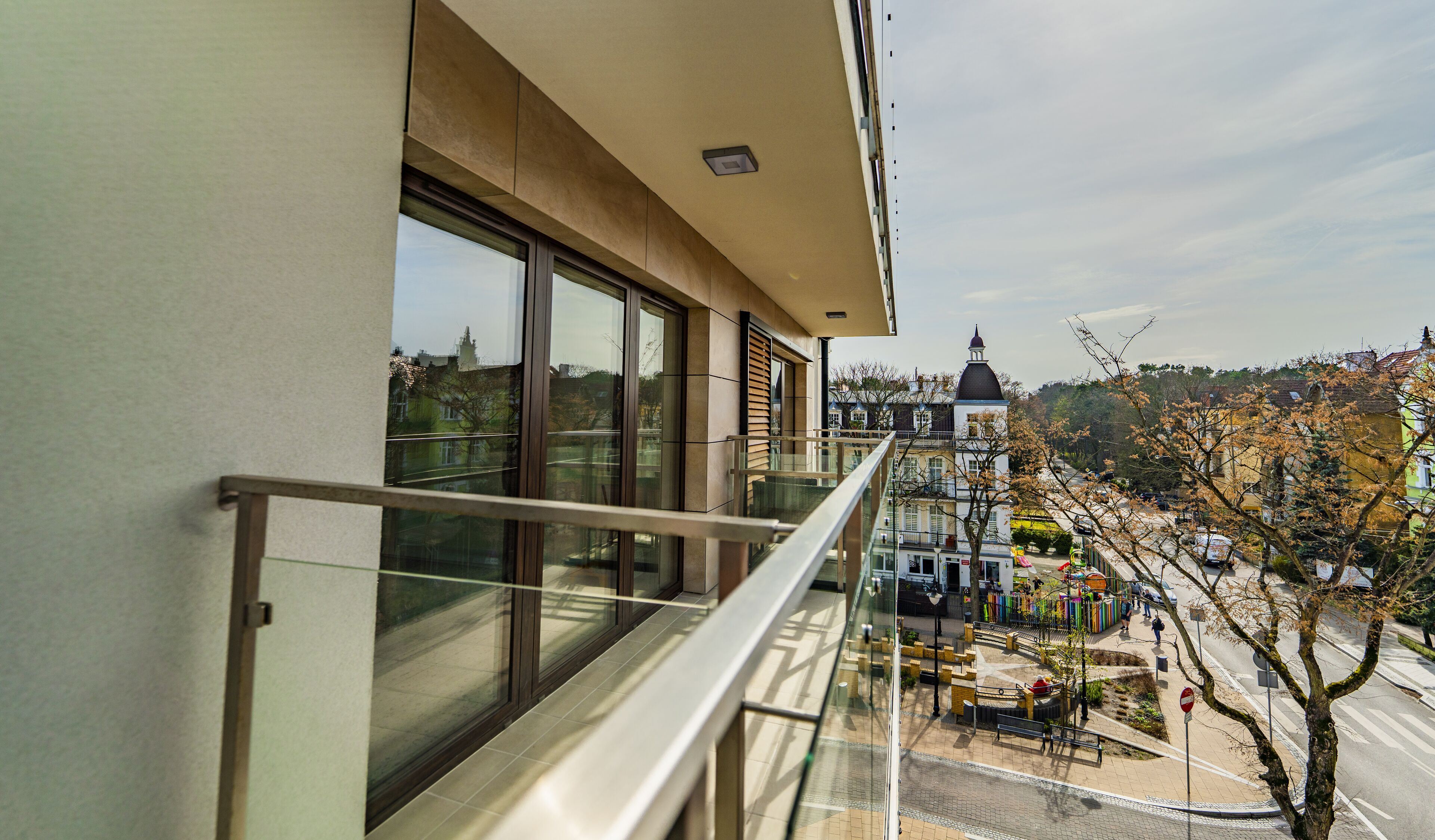 A balcony with a view of a town square, including a church and a playground.