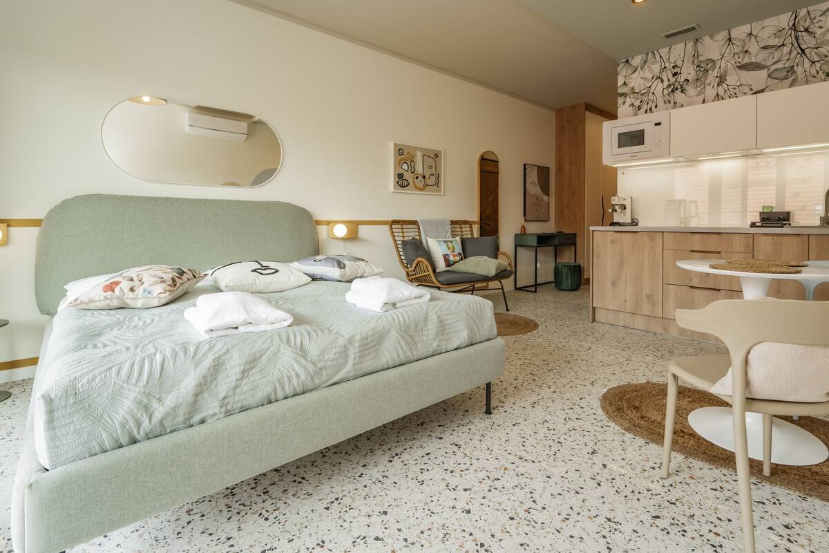 Una habitación de hotel moderna con cama, zona de estar, kitchenette y baño.
