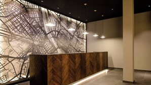 Zona de recepción con mostrador de madera, panel de mapa y lámparas colgantes.