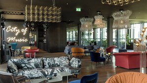 Un área de descanso moderna con diversos asientos, incluyendo sofás y sillones, y un letrero llamativo que dice 'City of Music'.