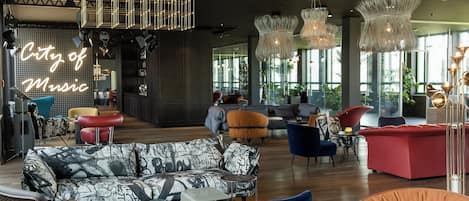 A modern lounge area with a mix of seating options, including sofas and chairs, and a prominent 'City of Music' sign.