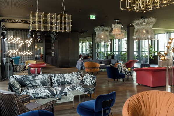 A modern lounge area with a mix of seating options, including sofas and chairs, and a prominent 'City of Music' sign.