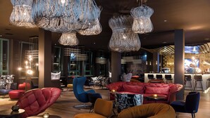 Un área de estar moderna con asientos cómodos, elegantes luminarias y un bar al fondo.