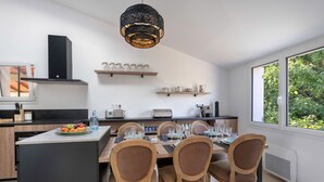 Een moderne keuken met een centraal eiland, houten stoelen en een eettafel voor zes personen.