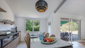 Een moderne keuken met een marmeren aanrecht, een fruitschaal en een eethoek met stoelen.