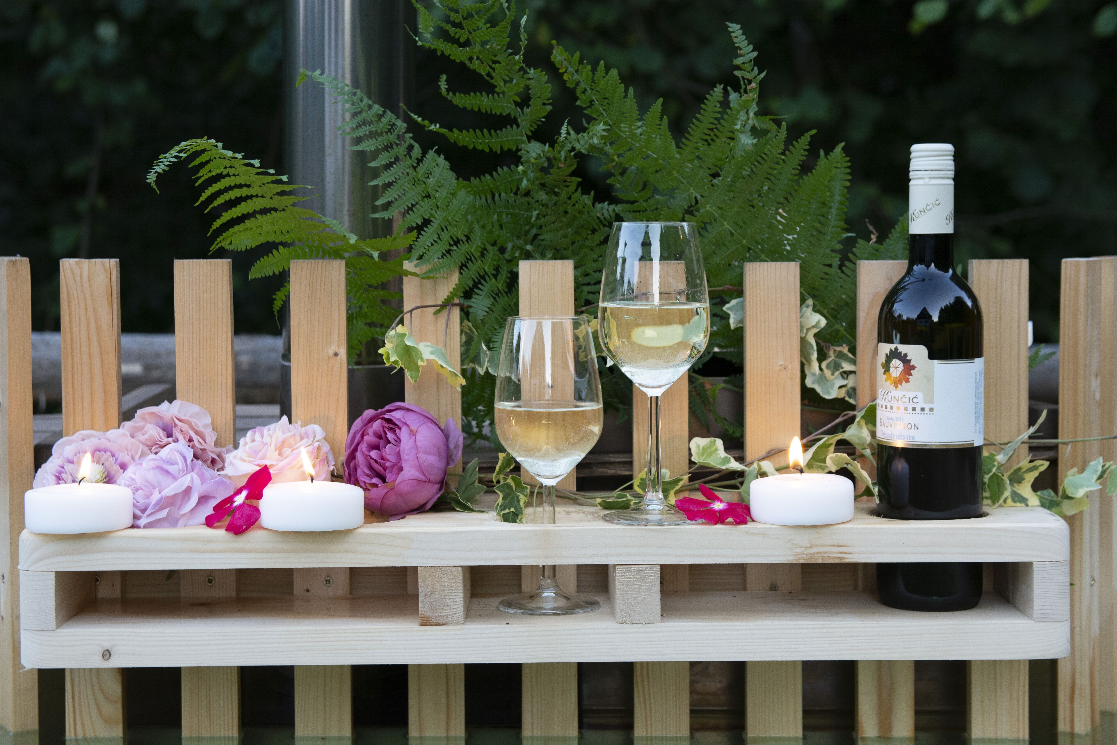 Ein Holztisch mit Kerzen, Blumen und Weingläsern.
