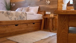 Una cama de madera con cabecera, mesita de noche y mesilla.