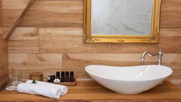 Une salle de bain avec un meuble-lavabo en bois, un lavabo blanc, un miroir à cadre doré et un mur en bois.