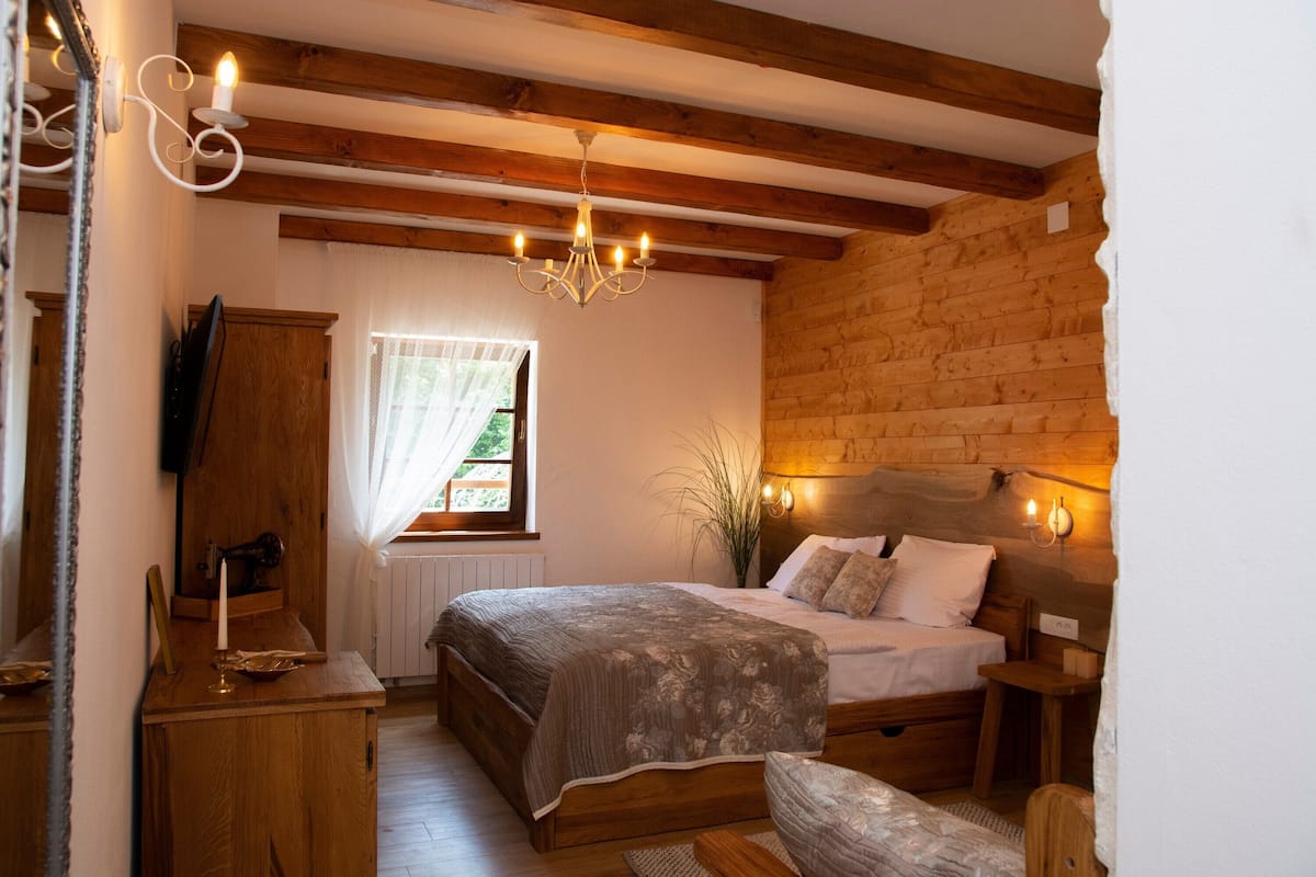 Ein gemütliches Schlafzimmer mit einem hölzernen Bett, einem Nachttisch, einer Kommode und einer Chandelier.
