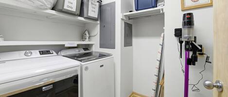 A laundry room with a washing machine, dryer, and a vacuum cleaner.
