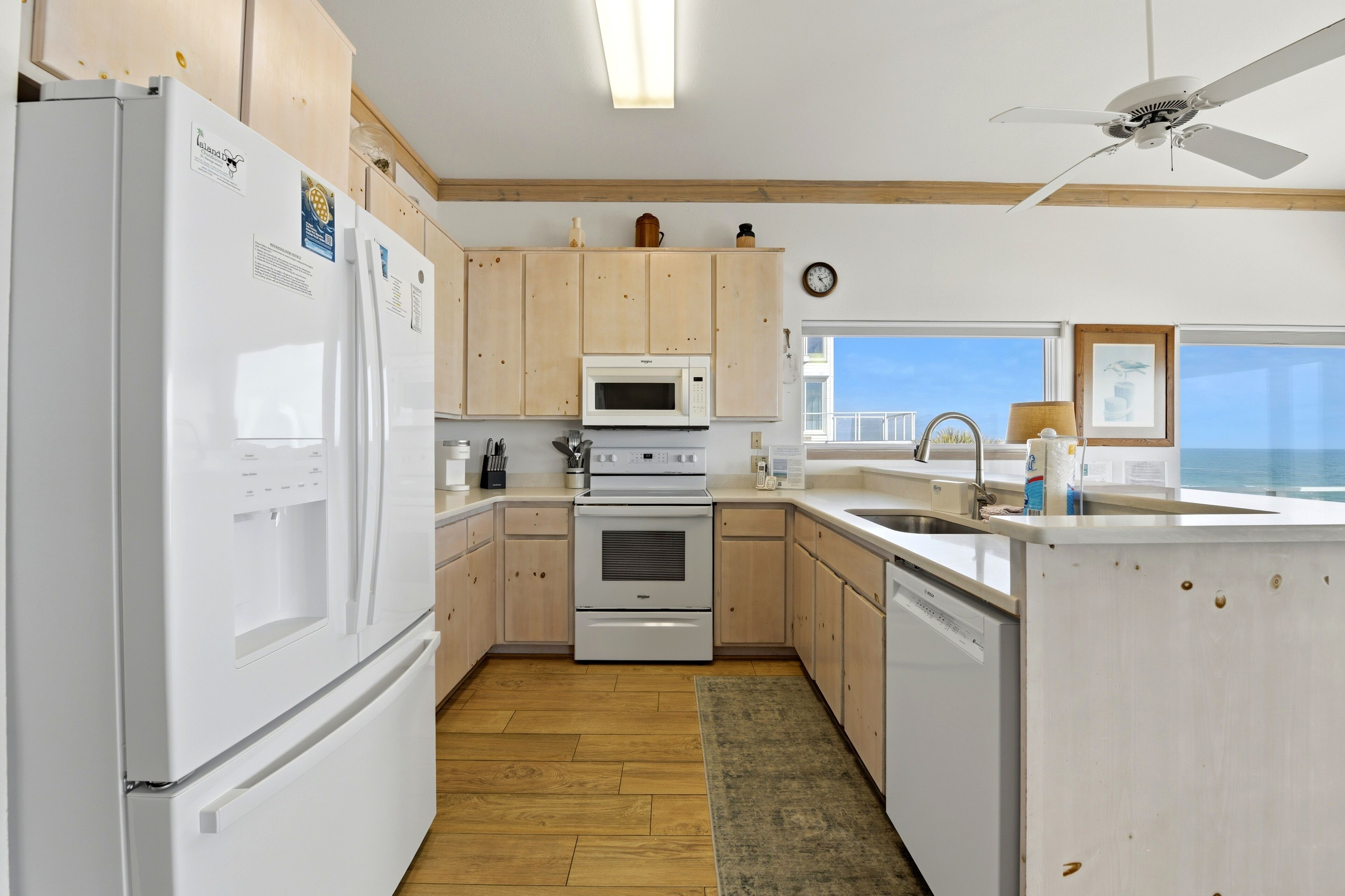 A modern kitchen with wooden cabinets, white appliances, a microwave, oven, and a dishwasher.