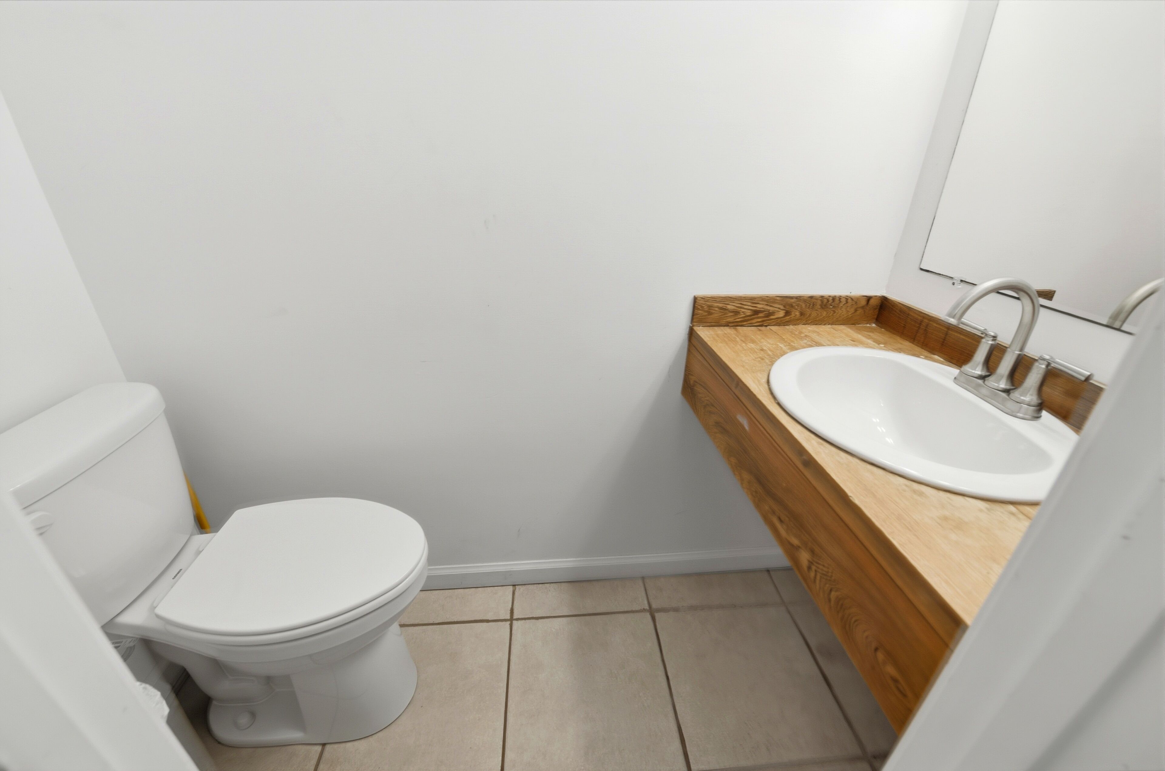 Une petite salle de bain avec des toilettes blanches, un meuble-lavabo en bois et un miroir.