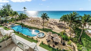 Un resort con piscina, zona de playa y palmeras.