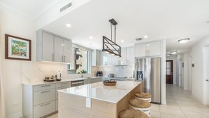 Una cocina moderna con una isla grande, armarios blancos y una lámpara colgante.