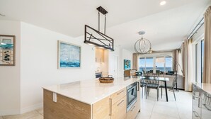 Una cocina moderna con una isla central, armarios de madera y un comedor con sillas y una mesa.