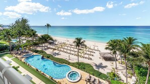 A resort with a swimming pool, beach, and palm trees.