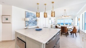 A modern kitchen with a marble countertop, stainless steel appliances, and a dining area with a round table and chairs.