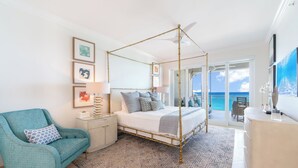 A four-poster bed with a balcony, a teal armchair, and artwork on the walls.