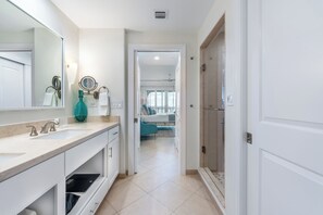Une salle de bain moderne avec un grand miroir, deux lavabos et un espace douche.