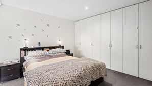 A bedroom with a bed, bedside tables, a wardrobe, and wall decals. - Spindrift Point Lonsdale (Point Lonsdale)