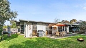 A single-story house with a patio area, a barbecue grill, and a dining table with chairs. - Spindrift Point Lonsdale (Point Lonsdale)