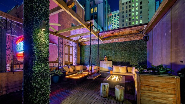 An outdoor seating area with wooden furniture, a fire feature, and a vertical garden wall. - Printers Alley PH *10,000 sq ft* Walk to Broadway (Nashville)