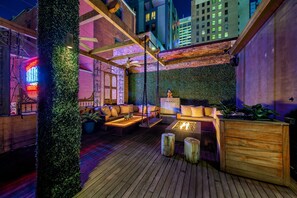 Un espacio al aire libre con mobiliario de madera, una chimenea y una pared vertical cubierta de jardín.