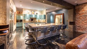 A modern kitchen with a central island, bar stools, and a stone accent wall. - Printers Alley PH *10,000 sq ft* Walk to Broadway (Nashville)