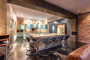 Una cocina moderna con una isla central, taburetes de bar y una pared decorativa de piedra.