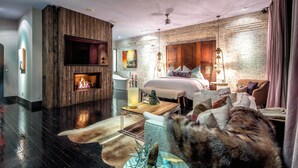 A modern hotel room with a fireplace, a large bed, a sitting area, and a cat. - Printers Alley PH *10,000 sq ft* Walk to Broadway (Nashville)