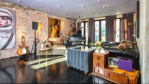 A spacious living room with a grand piano, a large painting, and a brick wall. - Printers Alley PH *10,000 sq ft* Walk to Broadway (Nashville)