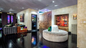 A modern lobby with a brick wall, a round seating area, and a bar with a neon sign. - Printers Alley PH *10,000 sq ft* Walk to Broadway (Nashville)