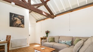 Ein gemütliches Wohnzimmer mit Holzboden, einem beigen Sofa, einem Holztisch und einem Gemälde eines Stiers an der Wand.