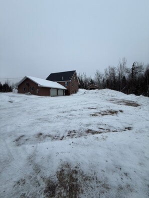A large, single-story house with a sloped roof and a garage. - Back Lake Views! Sleeps 12, Flat Rate, Direct ATV & Private Snowmobile Access! (Pittsburg)