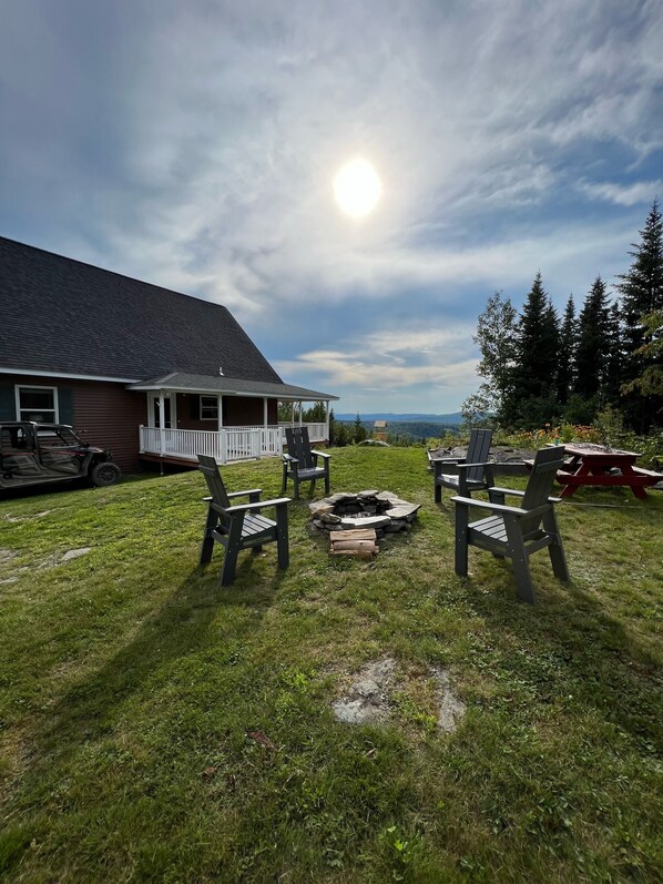 A backyard with a fire pit, outdoor seating, and a view of mountains. - Back Lake Views! Sleeps 12, Flat Rate, Direct ATV & Private Snowmobile Access! (Pittsburg)