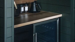 Una cocina con estantes de madera, una cafetera y frascos.
