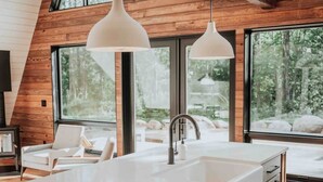 A modern kitchen with a large island, wooden cabinetry, and pendant lighting.