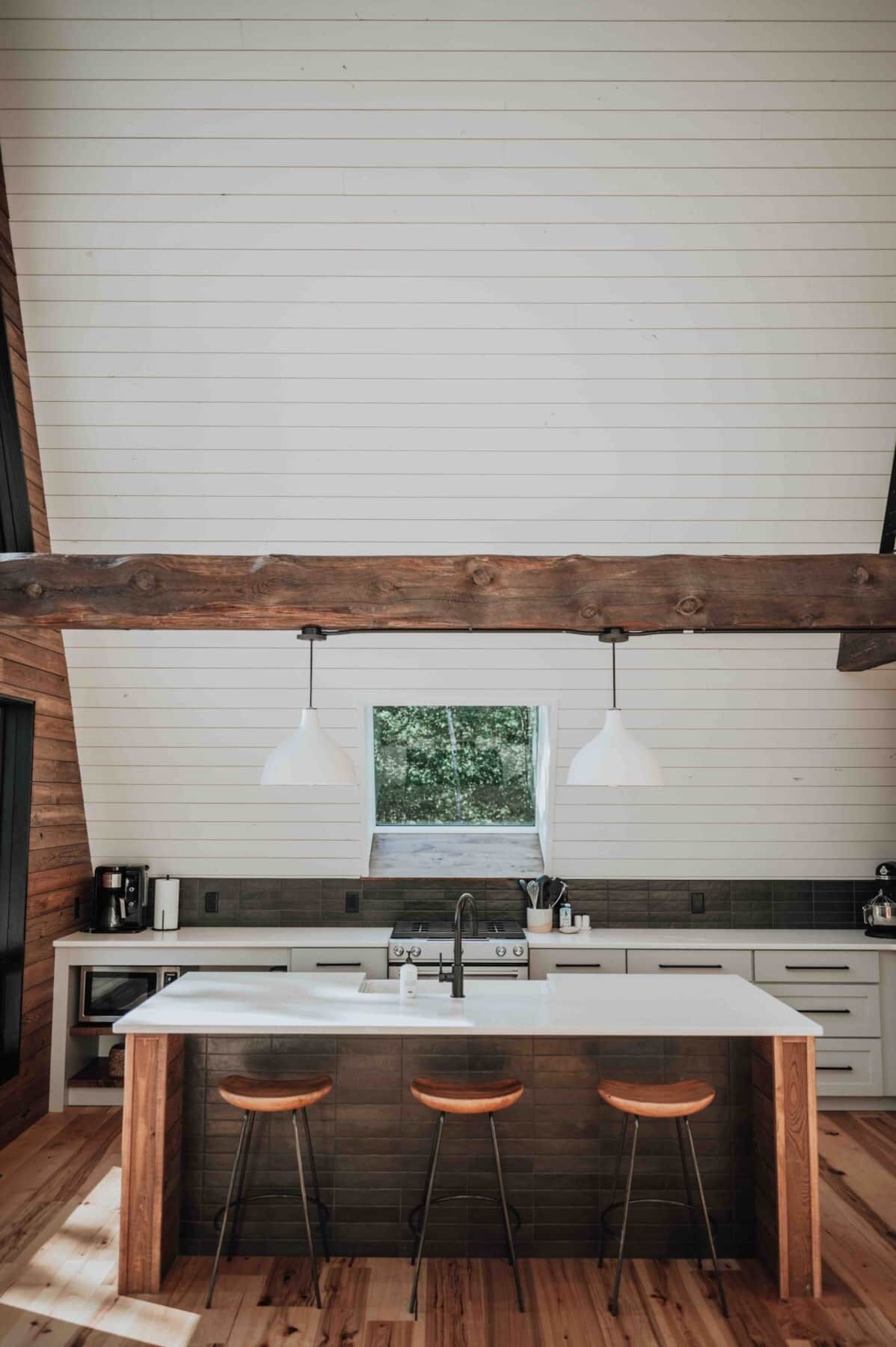 A modern kitchen with a central island, bar stools, and pendant lighting.