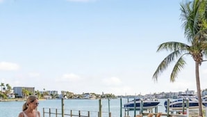 A poolside area with lounge chairs, a pool, and a view of the marina.
