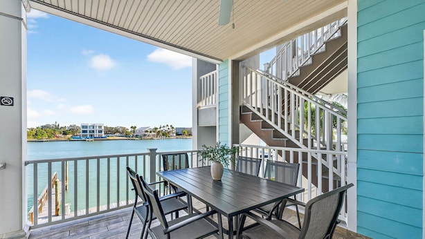 A balcony with a table and chairs, a view of the water, and a staircase.