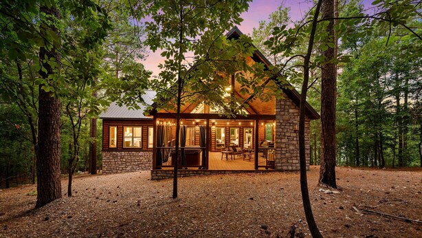 A rustic cabin with a stone foundation and wooden exterior, surrounded by trees. - HIGH Luxe MODERN 1+ Bedroom New Construction July 2022! (Broken Bow)