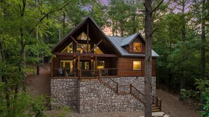 A log cabin with a stone foundation, wooden exterior, and a balcony. - HIGH Luxe MODERN 1+ Bedroom New Construction July 2022! (Broken Bow)