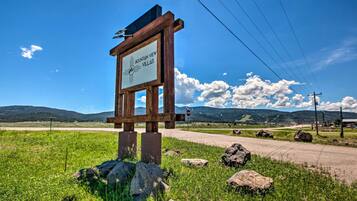 Un panneau en bois portant l’inscription « Mountain View Villas », avec en arrière-plan un ciel dégagé, un chemin de terre et des montagnes lointaines.