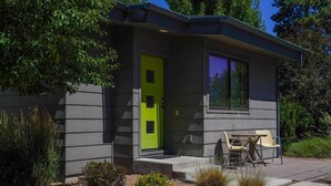 A modern house with a bright green door, a patio with a table and chairs, and a well-maintained garden.