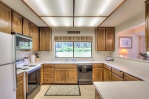 A kitchen with wooden cabinets, a built-in oven, a microwave, a dishwasher, and a window with a view of greenery. - Views to the golf course (Sleeps 10!) - 10 Aspen C (Blairsden)